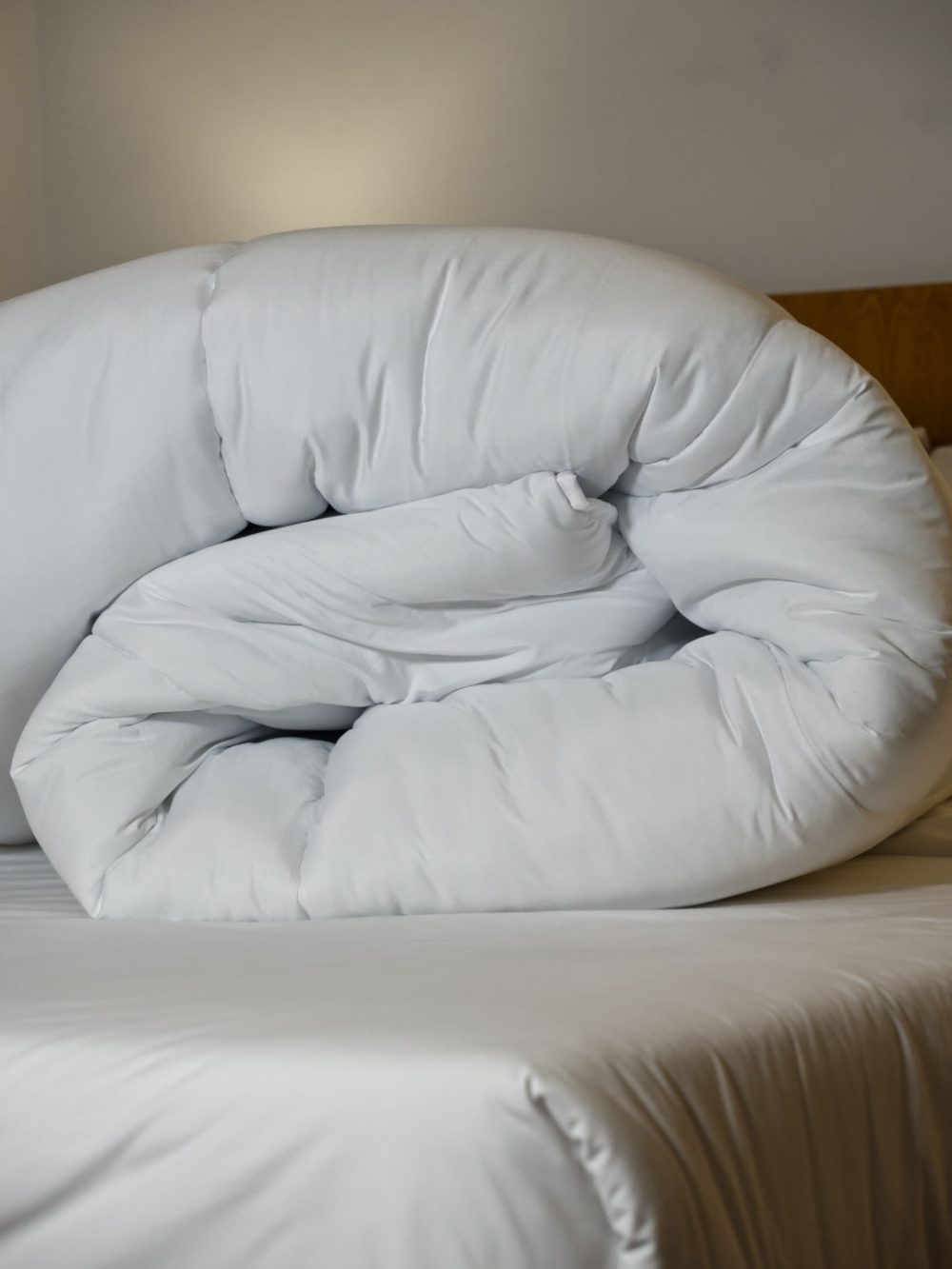 Edredão nórdico branco de 400g dobrado sobre a cama, mostrando o volume e suavidade do enchimento.